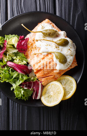 Lachs piccata mit Frischer gemischter Salat closeup auf einem Teller. Vertikal oben Ansicht von oben Stockfoto