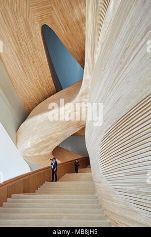 Gewundene Treppe in Holz verkleidet. Harbin Opernhaus, Harbin, China. Architekt: MAD, 2015. Stockfoto