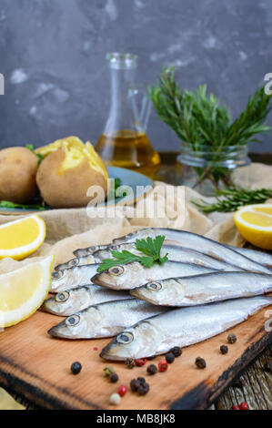 Gekochte Kartoffeln ungeschält in Felle, eine kleine gesalzene Fische der Ostsee Hering, Sprotten an einem hölzernen Tisch Stockfoto