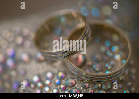 Passende Hochzeit gold Bands für Sie und Ihn, positioniert auf einem auffälligen Hintergrund goldener Seide Tuch mit Strass Kristalle Stockfoto