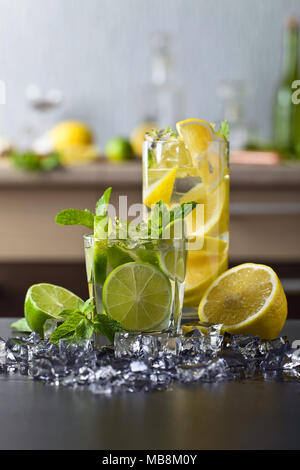 Cocktails mit Limette, Zitrone, Eis und Pfefferminze Blätter auf einem Schwarzen Tisch. Stockfoto