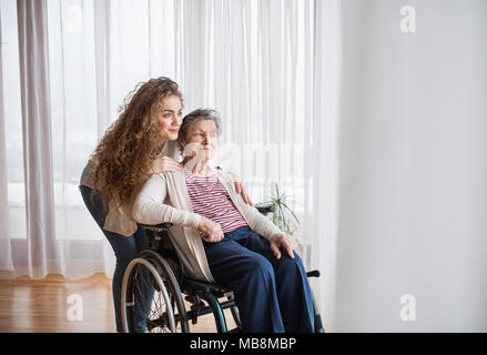 Ein junges Mädchen mit Großmutter zu Hause, umarmen sich. Stockfoto