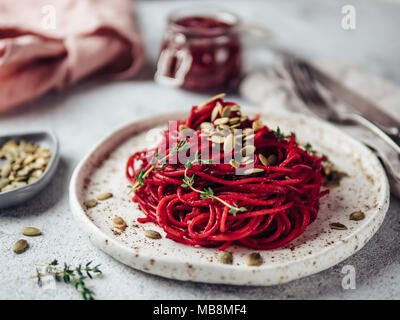 Gebratene rote Bete und Thymian Spaghetti mit Kürbiskerne in Handwerk Platte auf grauzement Hintergrund. Ideen und Rezepte für eine gesunde Vegane vegetarisches Abendessen. Selektive konzentrieren. Stockfoto