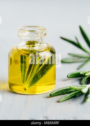 Rosmarin Öl. Rosemary wesentliches öl Öl in kleinen Fläschchen und Niederlassungen von frischem Rosmarin auf weißem Hintergrund. Kopieren Sie Platz für Text. Vertikale. Stockfoto