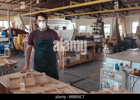 Junge Schreiner in seinem Studio Tragen von Arbeitskleidung Stockfoto