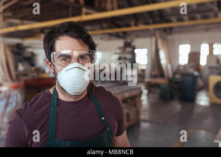 Junge woodworker mit Schutzkleidung in seiner Werkstatt Stockfoto