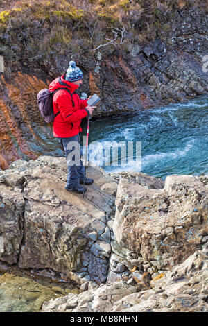 Mann mit Handy stehen auf Felsen an Fairy Pools, Fluss Spröde, Isle of Skye, Schottland, UK im März Stockfoto