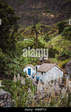 Häuser aus Stein im lokalen Stil mit Stroh gedeckten Dächer und blauen Fenstern zwischen üppigen grünen Vegetation und Landschaft. Santo Antao Kap Verde Stockfoto