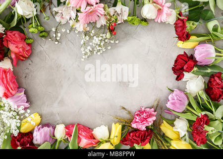 Schöne, bunte Blumen liegen um einen grauen Tabelle. Muttertag Geschenk Konzept. Stockfoto