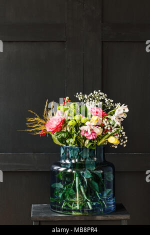 Big Bouquet von Frühling Blumen in einer Glasvase auf schwarzem Hintergrund. Muttertag Geschenk Konzept Stockfoto