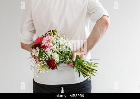 Elegante Mann hält einen Strauß Frühlingsblumen hinter seinem Rücken für sein Datum Stockfoto