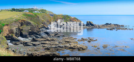 Ein Blick auf die felsigen Landzunge um Lizard Point in Cornwall, mit Lizard Lighthouse und Bootshaus, in Aussicht. Stockfoto