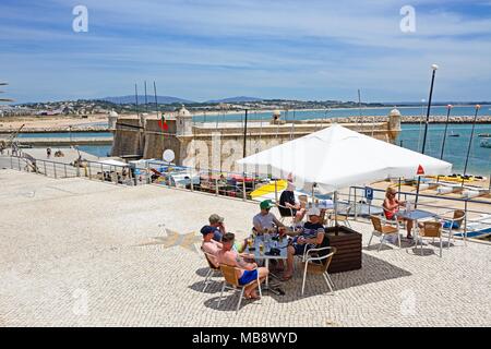 Ansicht der Ponta da Bandeira Fort mit Touristen entspannen in einem Straßencafé im Vordergrund, Lagos, Algarve, Portugal, Europa. Stockfoto