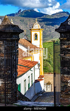 Blick auf eine von mehreren Kirchen und ihrem Glockenturm in Barock und koloniale Architektur der Stadt Ouro Preto in Minas Gerais mit seinen Bergen Stockfoto