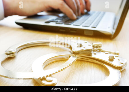 Computerkriminalität. Mann mit Laptop und Handschellen. Untersuchung Konzept. Stockfoto