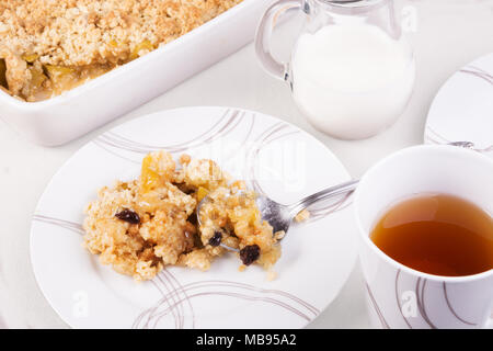 Kaffee serviert mit traditionellen britischen Apple oder Rhabarber crumble. Ein Teil auf der Platte und in einer Auflaufform bröckeln Stockfoto