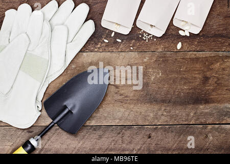 Generische Gartengeräte, Samen und Erde auf einem rustikalen Holztisch. Bild geschossen von oben im flachen Stil legen. Stockfoto