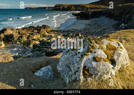 Großes Moos bedeckt Rock mit Blick auf den schönen sandigen Bucht bei Garry Strand auf der Isle of Lewis an einem sonnigen Tag im Frühling. Stockfoto