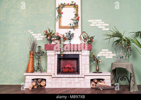 Innenansicht der Ferienwohnung mit einer Wand mit einer dekorativen elektrischer Kamin, geschmückt mit Blumen Stockfoto