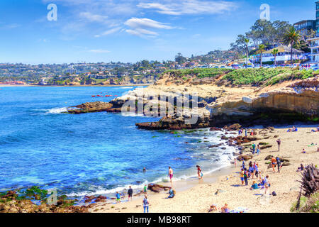 Beliebte Küstenstadt La Jolla Cove in San Diego mit einer Masse am Strand, Canoers auf dem Wasser, und eine Gruppe von Seelöwen auf den Felsen. Stockfoto