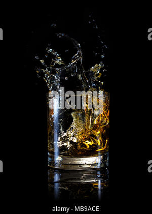 Splash in Glas Whiskey auf schwarzem Hintergrund Stockfoto