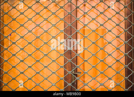 Jahrgang Geschlossen alte Holztür eines Home, Akzente mit einem Bügeleisen vergitterten Fenster, eisernen Türklopfer, Bügeleisen und Schrauben. Stockfoto