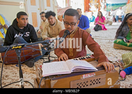 Ein Hindu-Junge im Teenageralter singt und spielt das Harmonium bei den Morgengottsdiensten im Tulsi Mandir-Tempel in South Richmond Hill, Queens, New York. Stockfoto