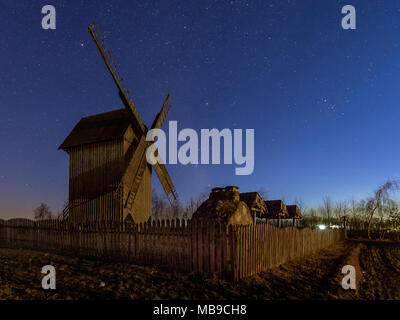 Alte hölzerne Windmühle bei Coutryside in der Nacht. Letzten Momente winter Konstellationen als Orion zu sehen. Ein klarer Himmel und der Himmel voller Sterne Stockfoto