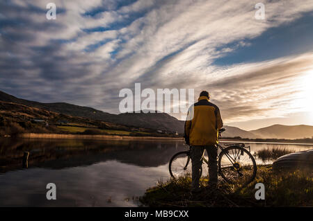 Ein Radfahrer stoppt den Sonnenuntergang in Ardara, County Donegal, Irland zu beobachten Stockfoto