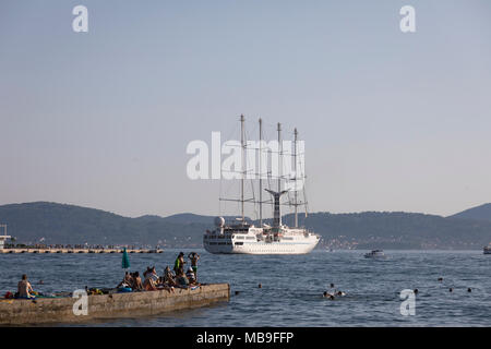 Schwimmen Menschen am Pier beobachten Kreuzfahrt Segelschiff SS "Wind Star" am Hafen von Zadar, Kroatien Stockfoto