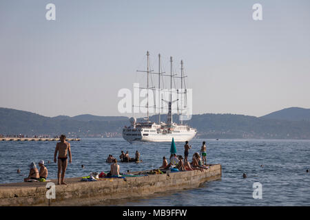 Schwimmen Menschen am Pier beobachten Kreuzfahrt Segelschiff SS "Wind Star" am Hafen von Zadar, Kroatien Stockfoto