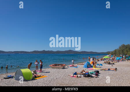 Touristen entspannen, sonnen und schwimmen am Strand am Mittelmeer, Zadar, Kroatien Stockfoto