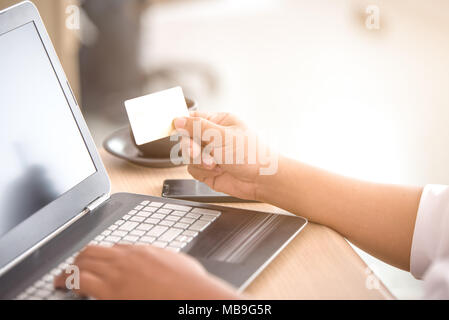 Hand, die Kreditkarte mit Laptop, junger Mann Einkaufen online per Kreditkarte Stockfoto