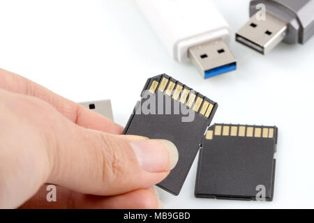 Hand hält SD-Card, Speicherkarte gegen usb, flash drive auf weißem Hintergrund. Stockfoto