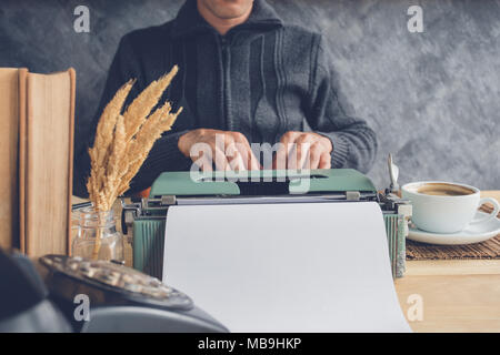 Hand des Menschen arbeiten mit Schreibmaschine und eine Tasse Kaffee im Café Stockfoto