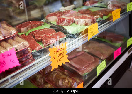 Ausgewählte Teilstücke von Fleisch, frisch Fleisch auf Tabletts in einer Glasfront Metzgerei Zähler mit bunten Preis tags angezeigt. Stockfoto