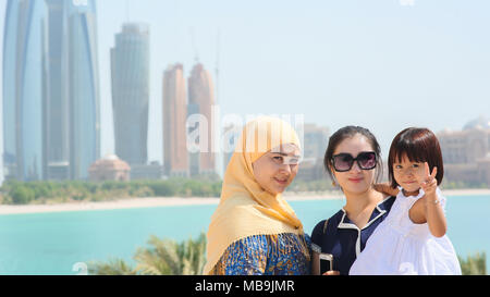 Abu Dhabi, VAE - 20. August 2014: Touristen für einen Fotografen im Hintergrund von Abu Dhabi Wolkenkratzer posing Stockfoto