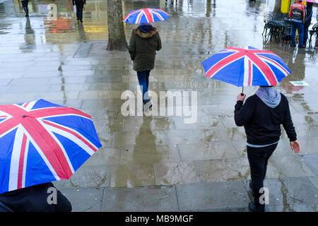 Fußgänger, die im Regen mit den Regenschirmen von Union Jack laufen, London, Großbritannien Stockfoto