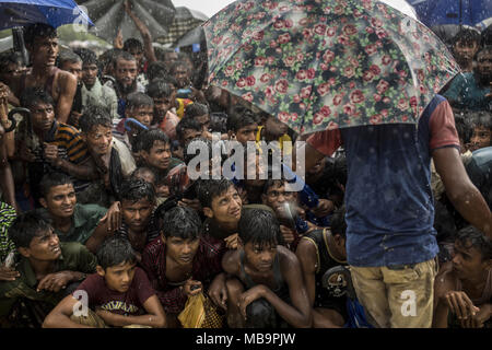 Coxs Bazar, Bangladesch. 28 Sep, 2017. Dutzende Männer warten im Regen für etwas in der Balukhali Flüchtlingslager zu essen. verschiedene NGOs essen täglich verteilen, aber es gibt so viele Menschen, die in einigen Orten gibt es große Warteschlangen. Bangladeshi Soldaten und freiwilligen Kontrolle, dass Niemand überspringt die Umdrehung zwingen, die Flüchtlinge zu sitzen bleiben. 9/26/2017. Credit: Olmo Calvo/ZUMA Draht/Alamy leben Nachrichten Stockfoto