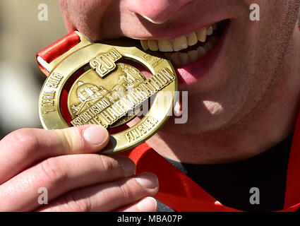 Prag, Tschechische Republik. 07 Apr, 2018. Ein Läufer Geschmack seine Medaille nach dem Prager Halbmarathon in Prag, Tschechische Republik, am 7. April 2018. Credit: Roman Vondrous/CTK Photo/Alamy leben Nachrichten Stockfoto