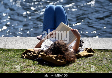 07 April 2018, Deutschland, Berlin: Eine junge Frau liest in der Sonne. Foto: Britta Pedersen/dpa-Zentralbild/dpa Stockfoto