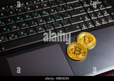 Bitcoins auf einem Laptop auf einen hölzernen Tisch. E-Commerce und der Währung. Stockfoto