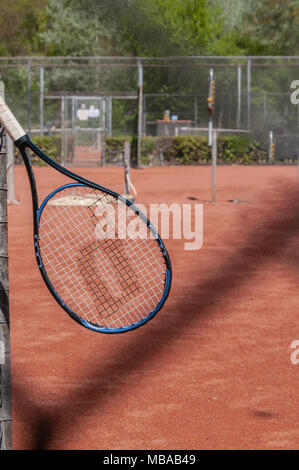 Ein Tennisschläger hängt schräg auf einem Zaun Stockfoto