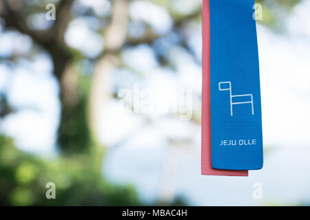 Jeju Olle Multifunktionsleiste als Marker für die Wanderwege mit Baum im Rücken, Seogwipo, Jeju Island, South Korea Stockfoto