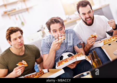 Gerne männliche Freunde essen Pizza und Fernsehen Stockfoto