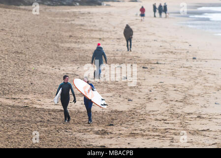 Surfer, die surfbretter nach dem Surfen auf den Fistral in Newquay Cornwall. Stockfoto