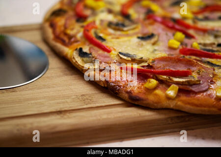 Nahaufnahme einer hausgemachten Pizza auf der Theke, in der Nähe der Pizza-Hobel Stockfoto