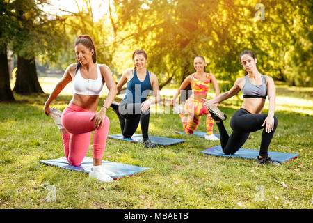 Vier schöne motivierte weibliche Freunde tun stretching Übung im City Park. Stockfoto