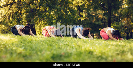 Vier schöne motivierte weibliche Freunde tun stretching Übung im City Park. Stockfoto