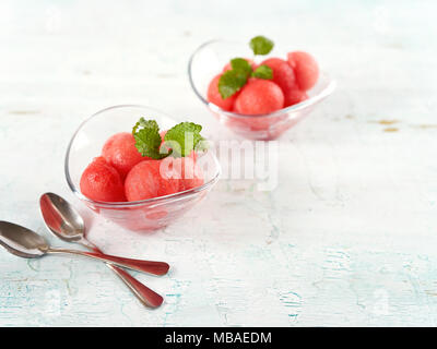 Wassermelone Schnitt mit Kugeln und im Glas serviert auf hölzernen Tisch Stockfoto